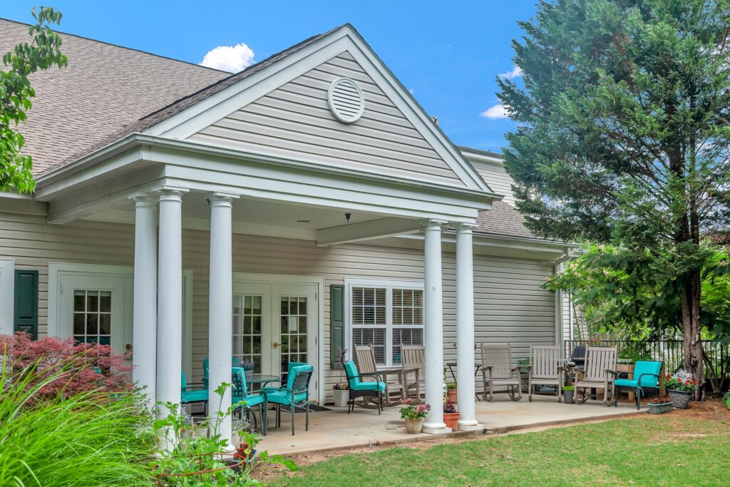 MG_7775 - The Willows of Easley Covered patio with rocking chairs and garden seating at The Willows of Easley, showcasing the peaceful setting of senior living near Greenville, SC.