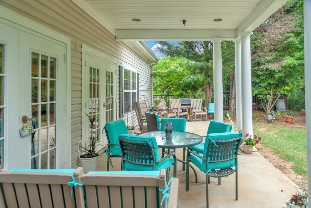 MG_7795 - The Willows of Easley The Willows of Easley outdoor patio with turquoise cushioned chairs surrounding a glass coffee table, and a row of brown reclining chairs.