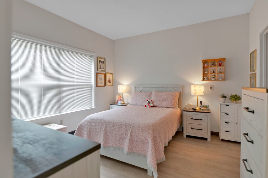 MG_7911 - The Willows of Easley A bedroom with a Queen-sized bed and pink bedding, two bedside tables with lamps, wall art, and two white dressers.