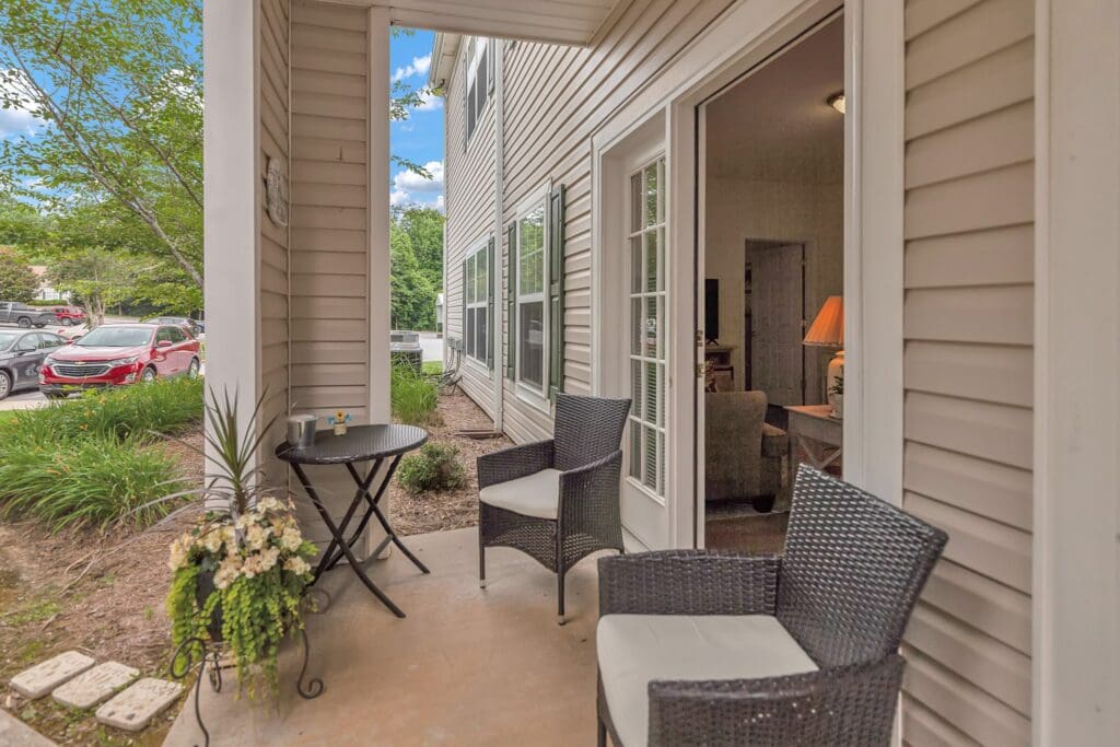 The Willows of Easley outdoor patio with two cushioned chairs, a small coffee table, and a potted plant.