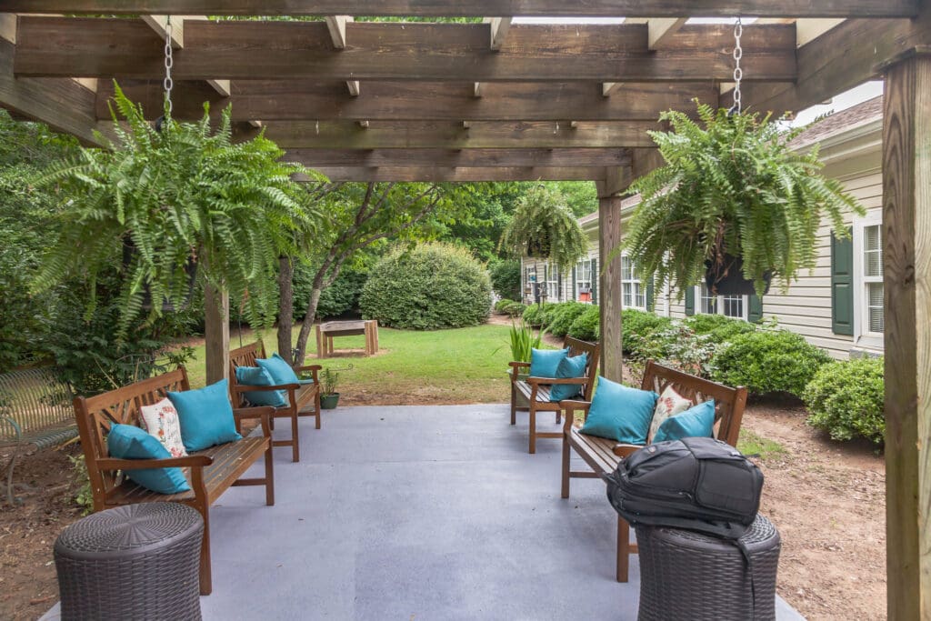 The Willows of Easley outdoor sitting area with brown benches and white and turquoise throw pillows on them.